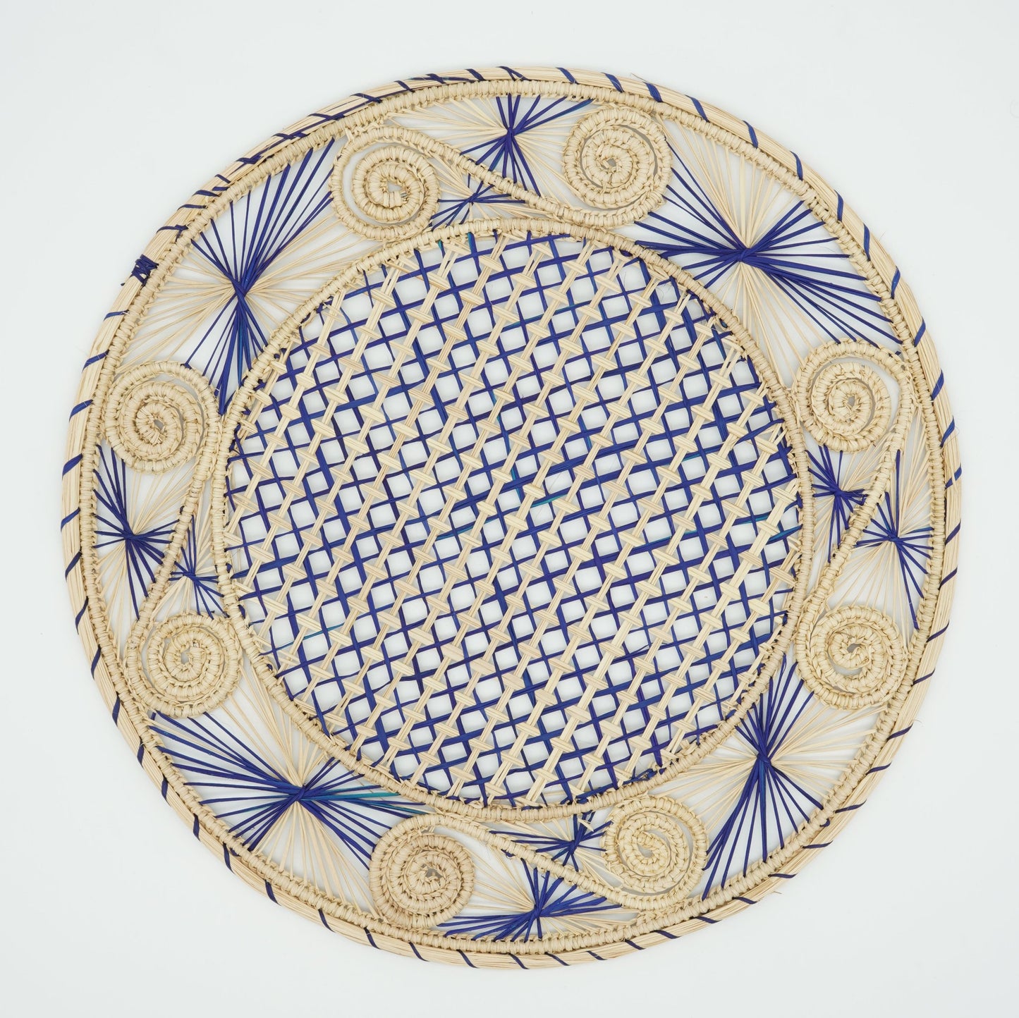 An overhead view of a woven placemat with a caracol (snail shell) pattern in natural and blue.