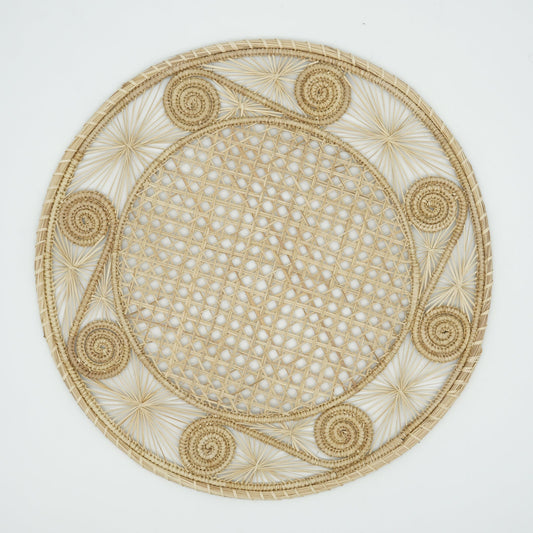 An overhead view of a woven placemat with a caracol (snail shell) pattern in natural.