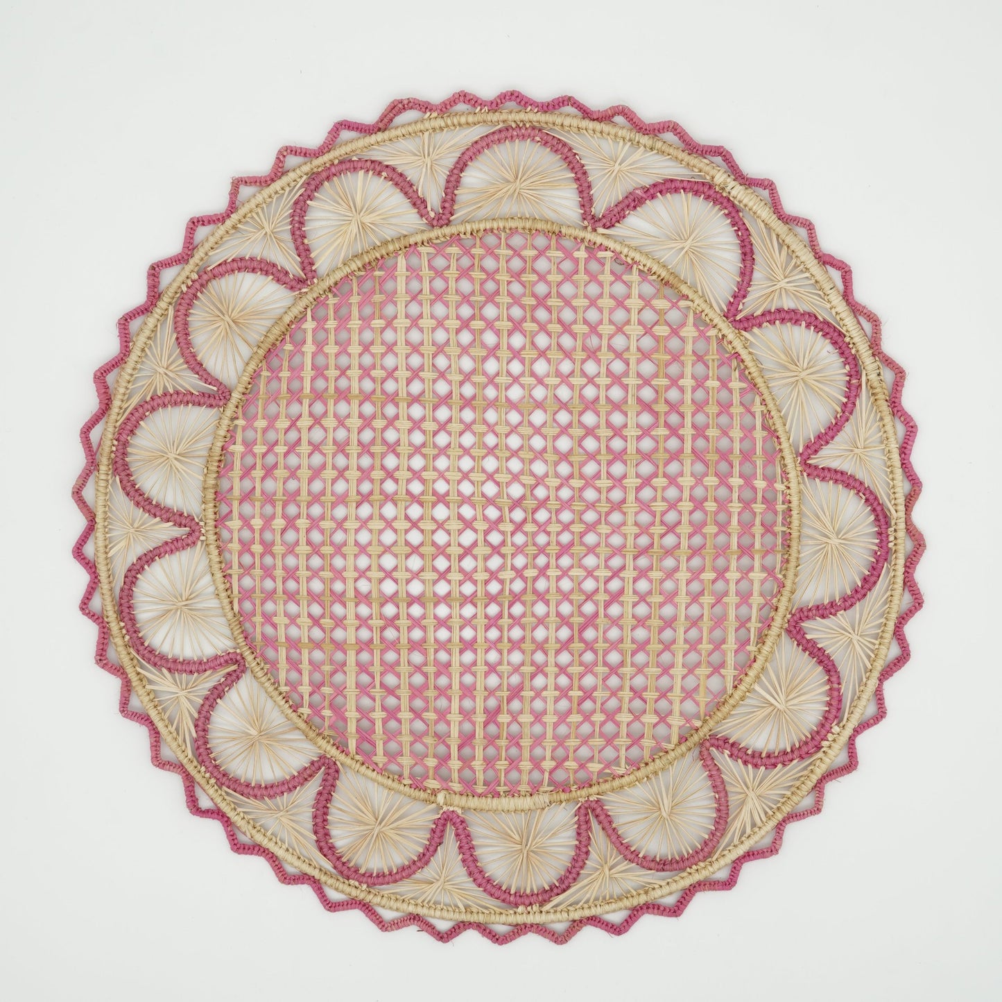 Overhead view of half moon patterned woven placemat in pink and natural.