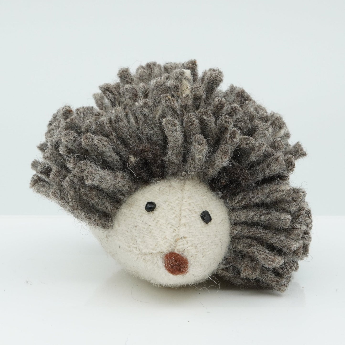 A gray and white wool rattle in the shape of a hedgehog.