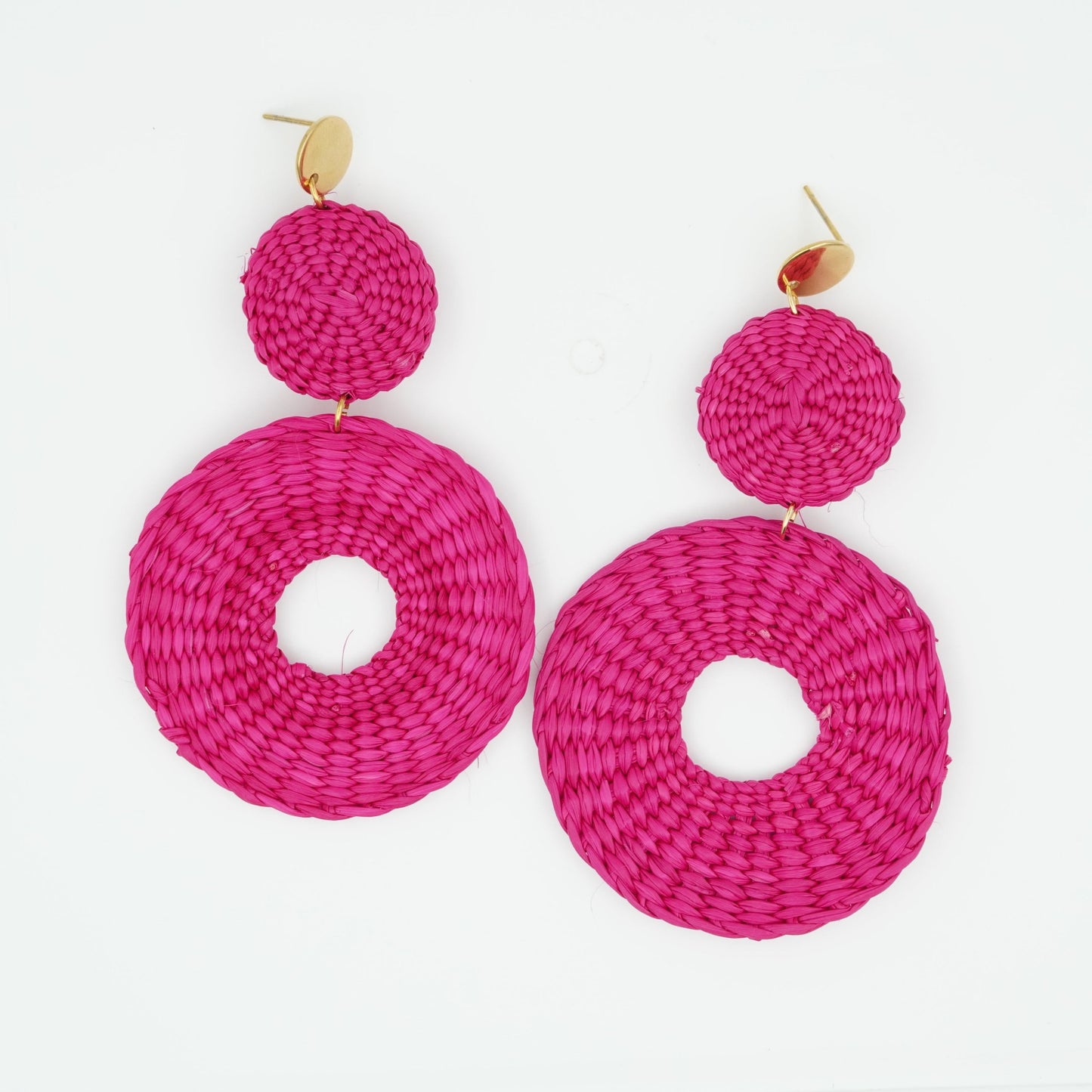 Overhead view of iraca fuchsia circle and dot woven earrings.