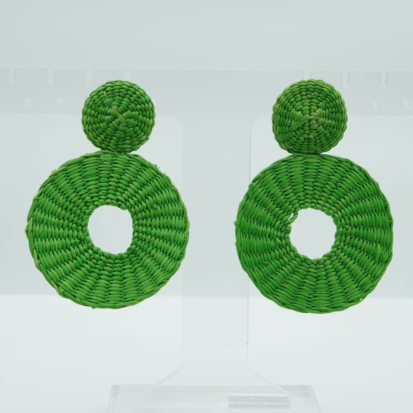 Head on view of iraca green circle and dot woven earrings.