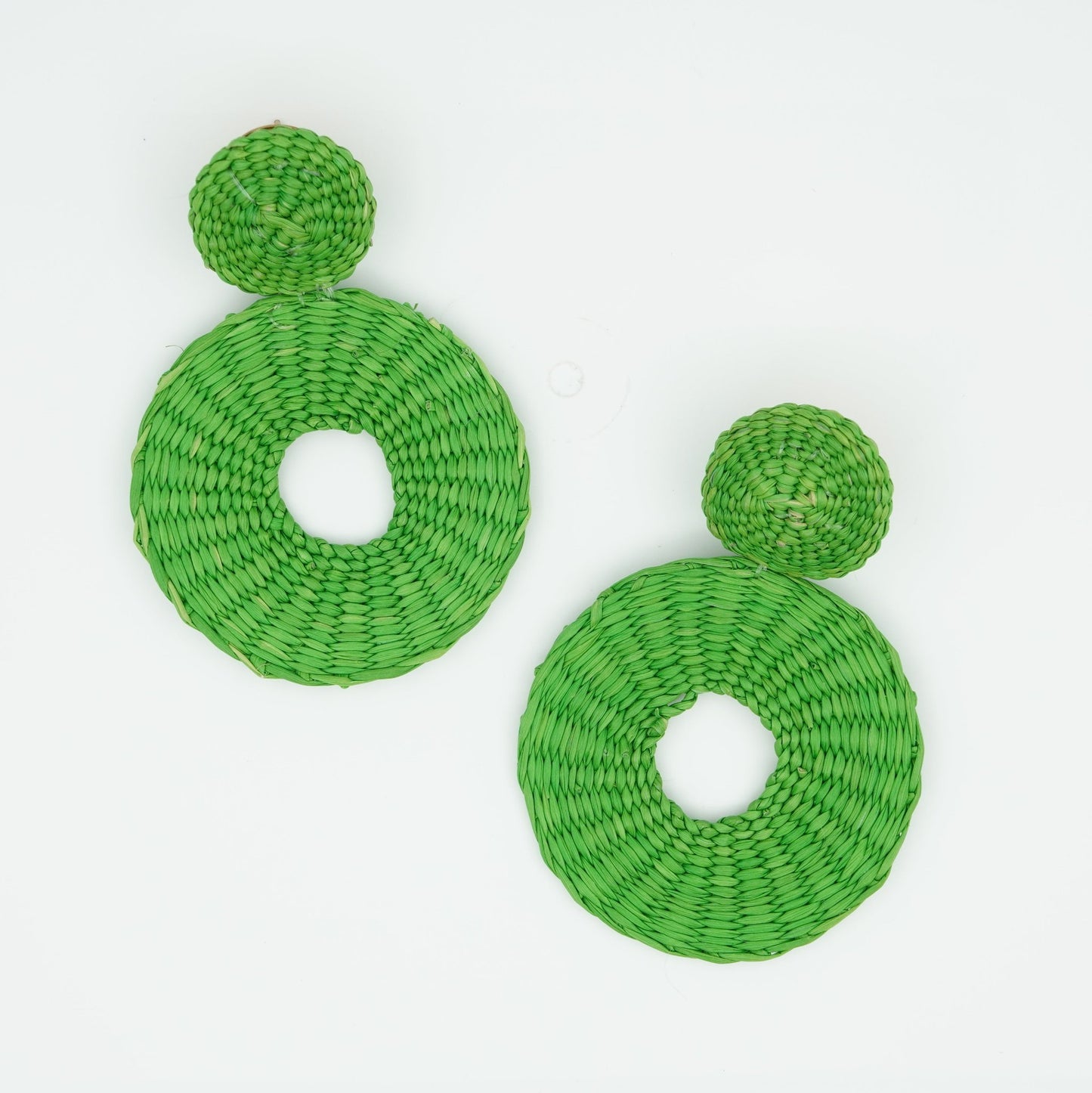 Overhead view of iraca green circle and dot woven earrings.