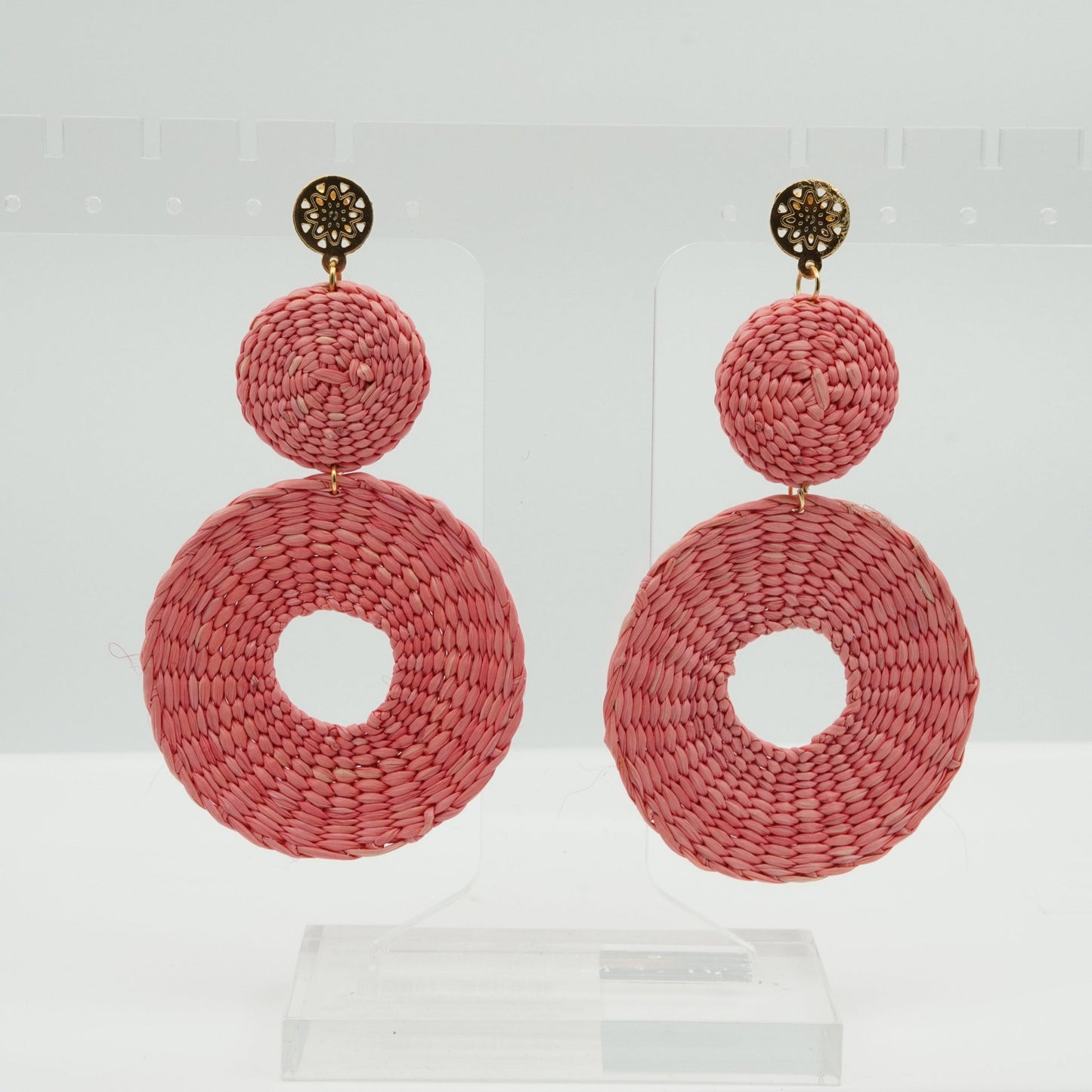 Head on view of iraca pink circle and dot woven earrings.