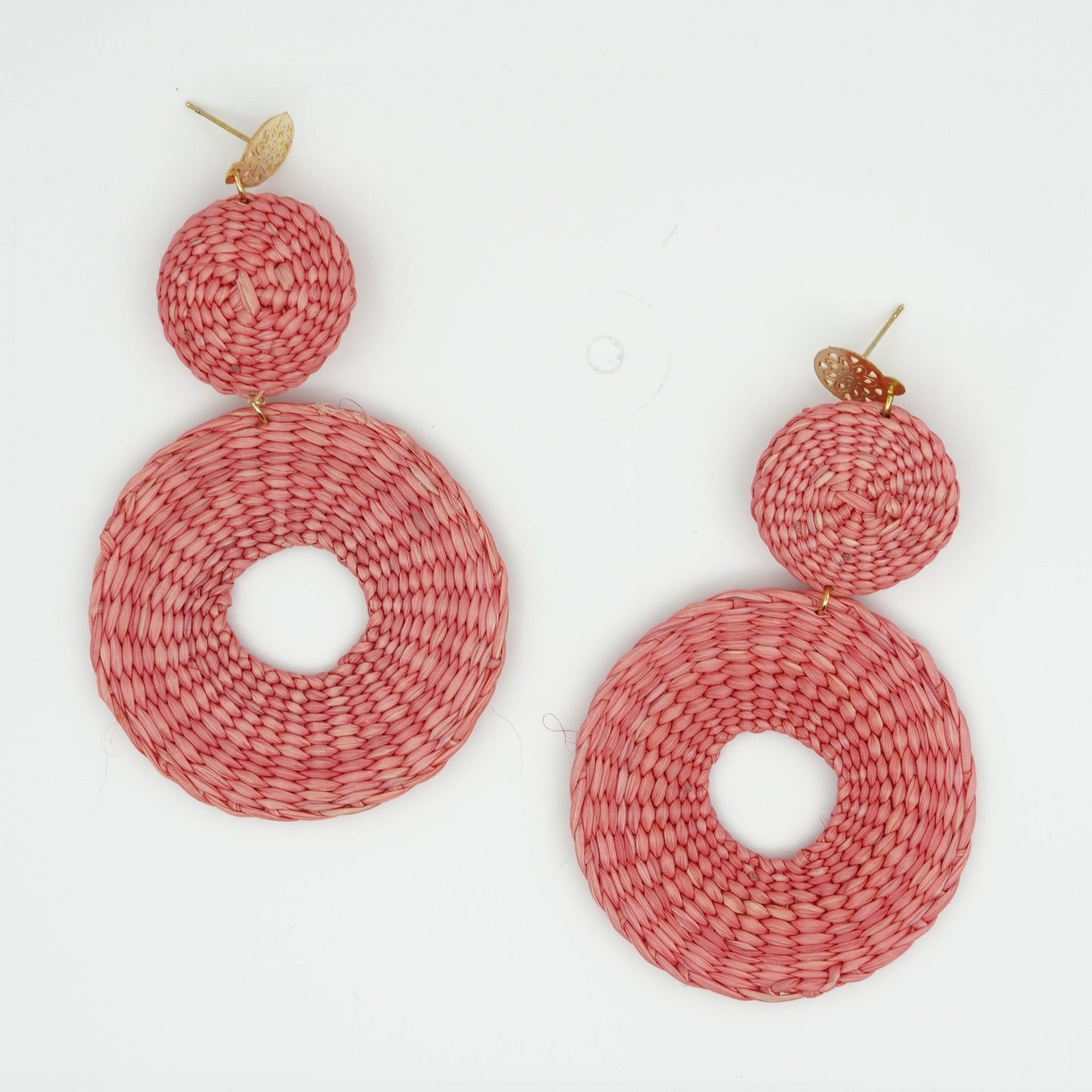 Overhead view of iraca pink circle and dot woven earrings.