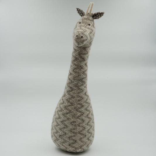 A gray and white wool doorstop in the shape of a giraffe.