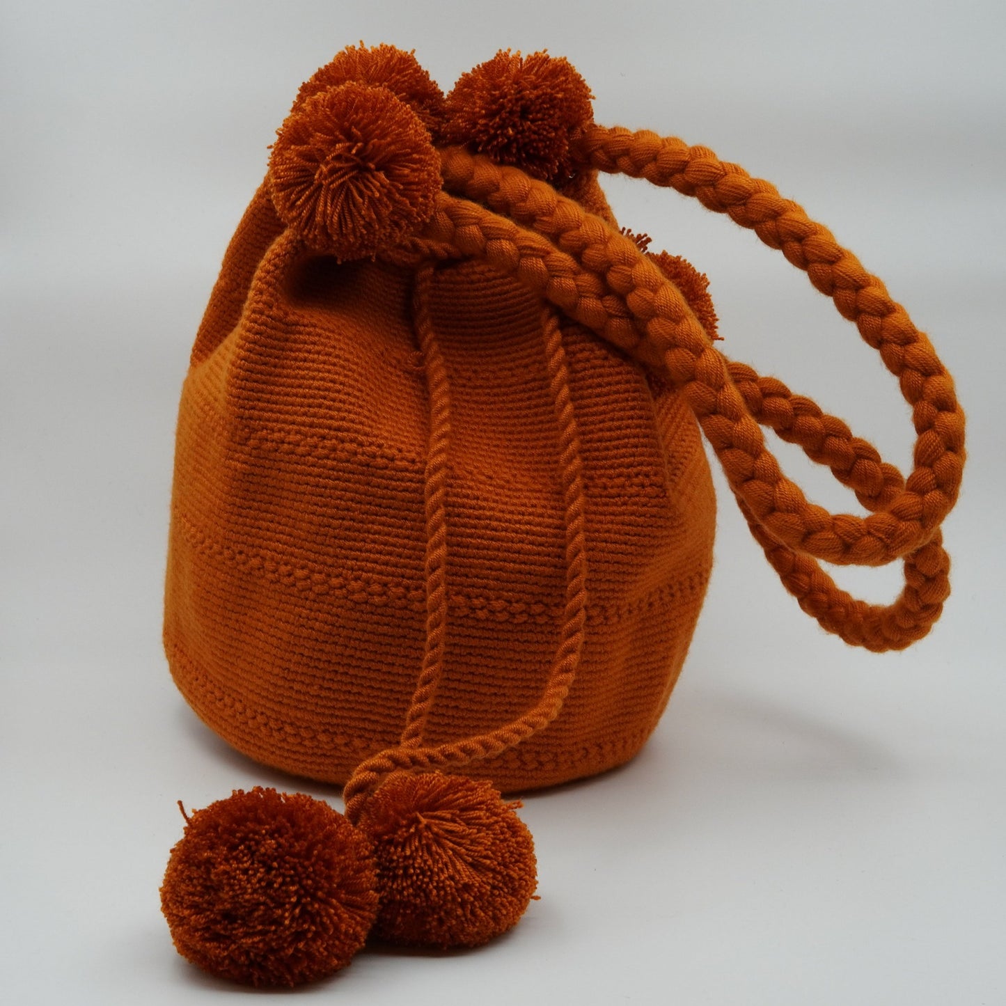 Large orange mochila woven handbag with pompoms.