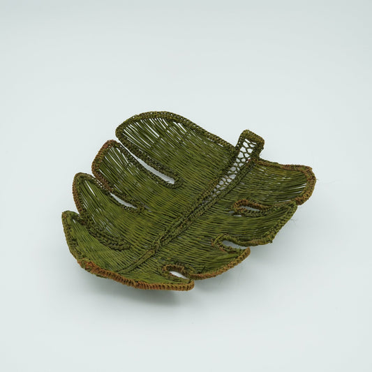 A green woven basket in the shape of a monstera leaf.