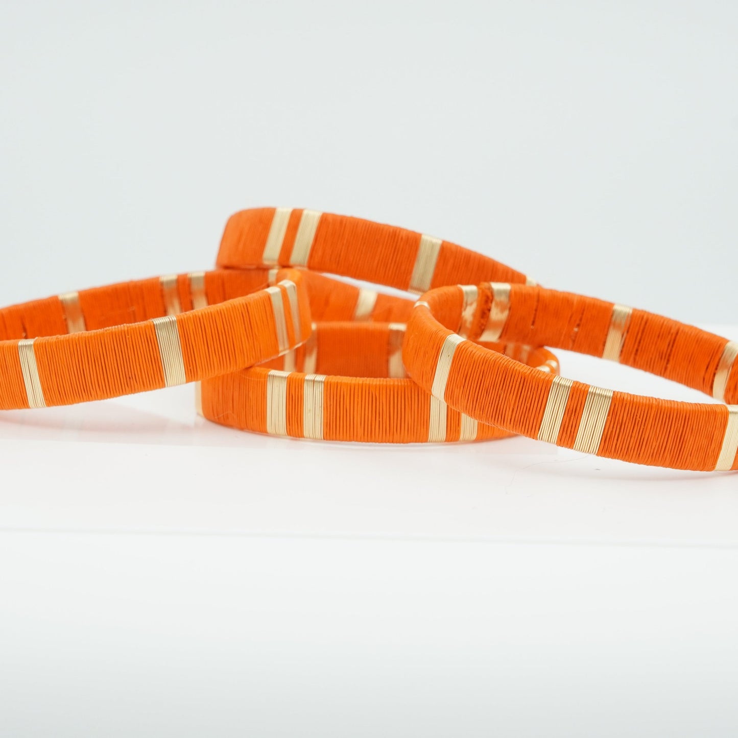 Bracelets made of orange werregue palm fiber and gold wire.