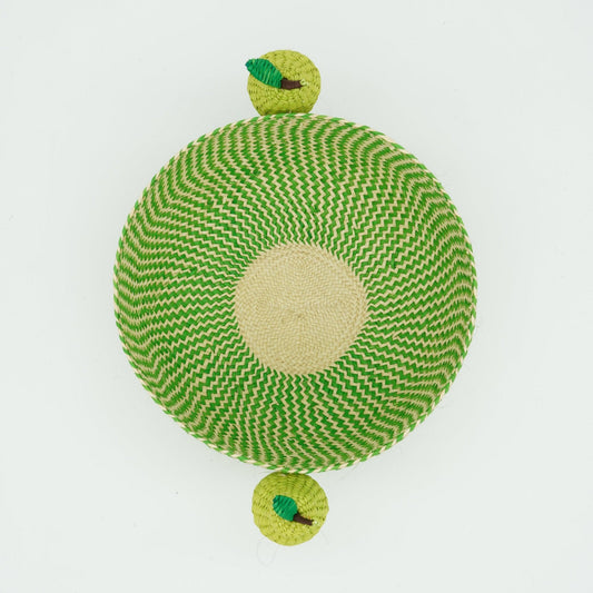 An overhead view of a green and natural woven basket featuring pears on the side.