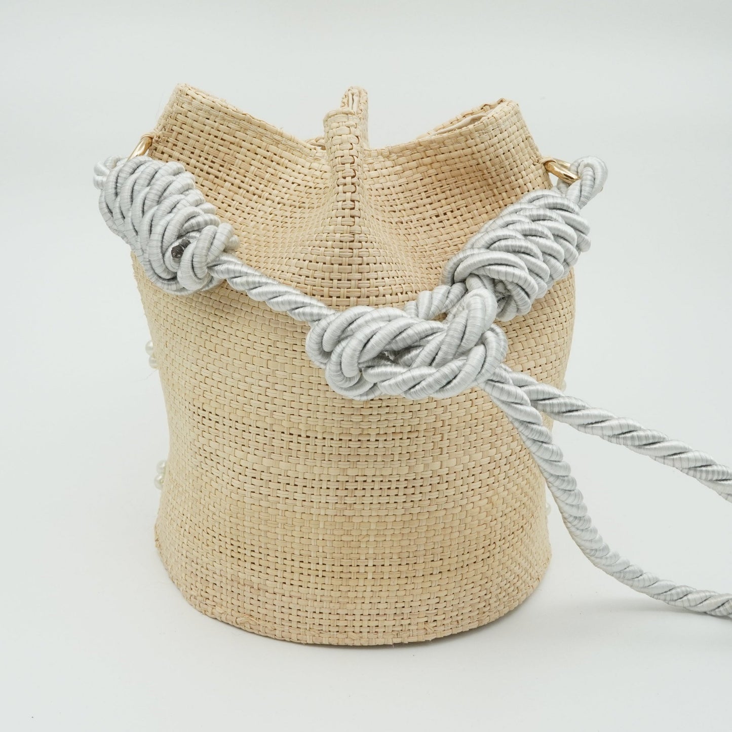 Back of woven pearl bucket bag with silver strap.