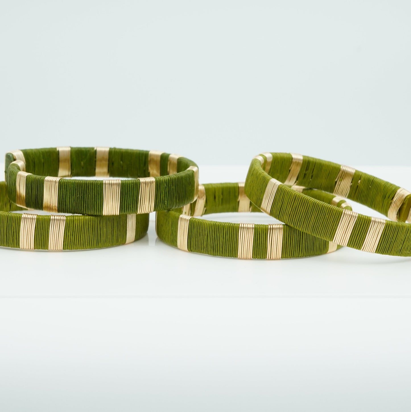 Bracelets made of sage green werregue palm fiber and gold wire.