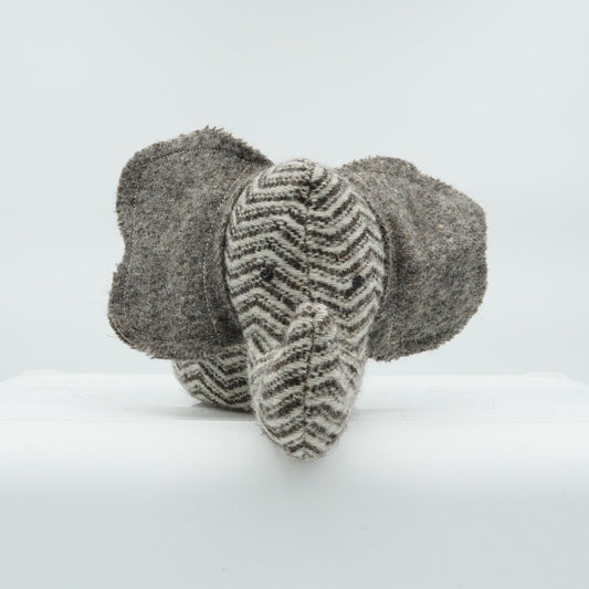 A gray and white wool doorstop in the shape of a small elephant.