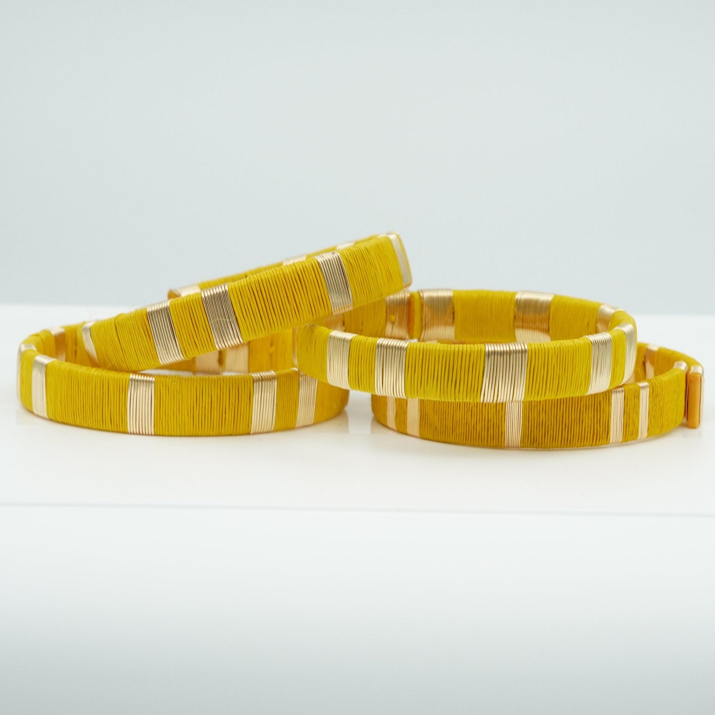 Bracelets made of yellow werregue palm fiber and gold wire.