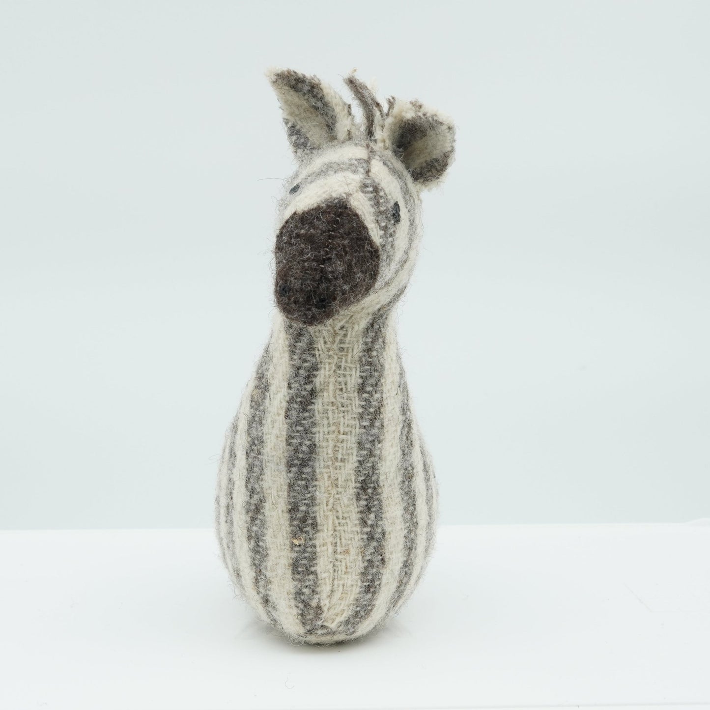 A gray and white wool rattle in the shape of a zebra.