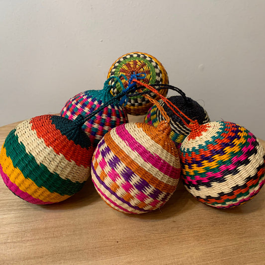 Group of colorful, ball-shaped woven ornaments made of iraca palm fiber.