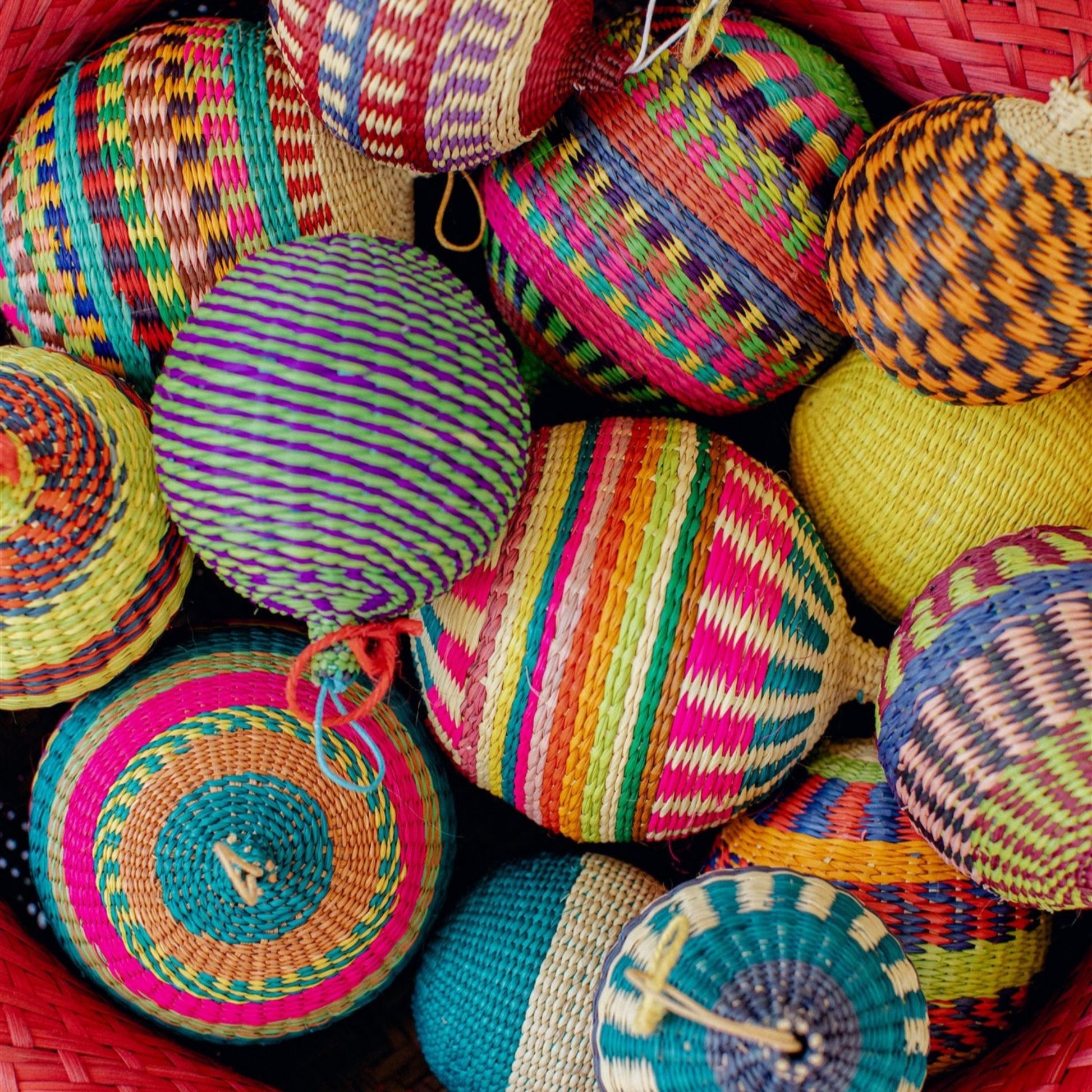 Group of colorful, ball-shaped woven ornaments made of iraca palm fiber.