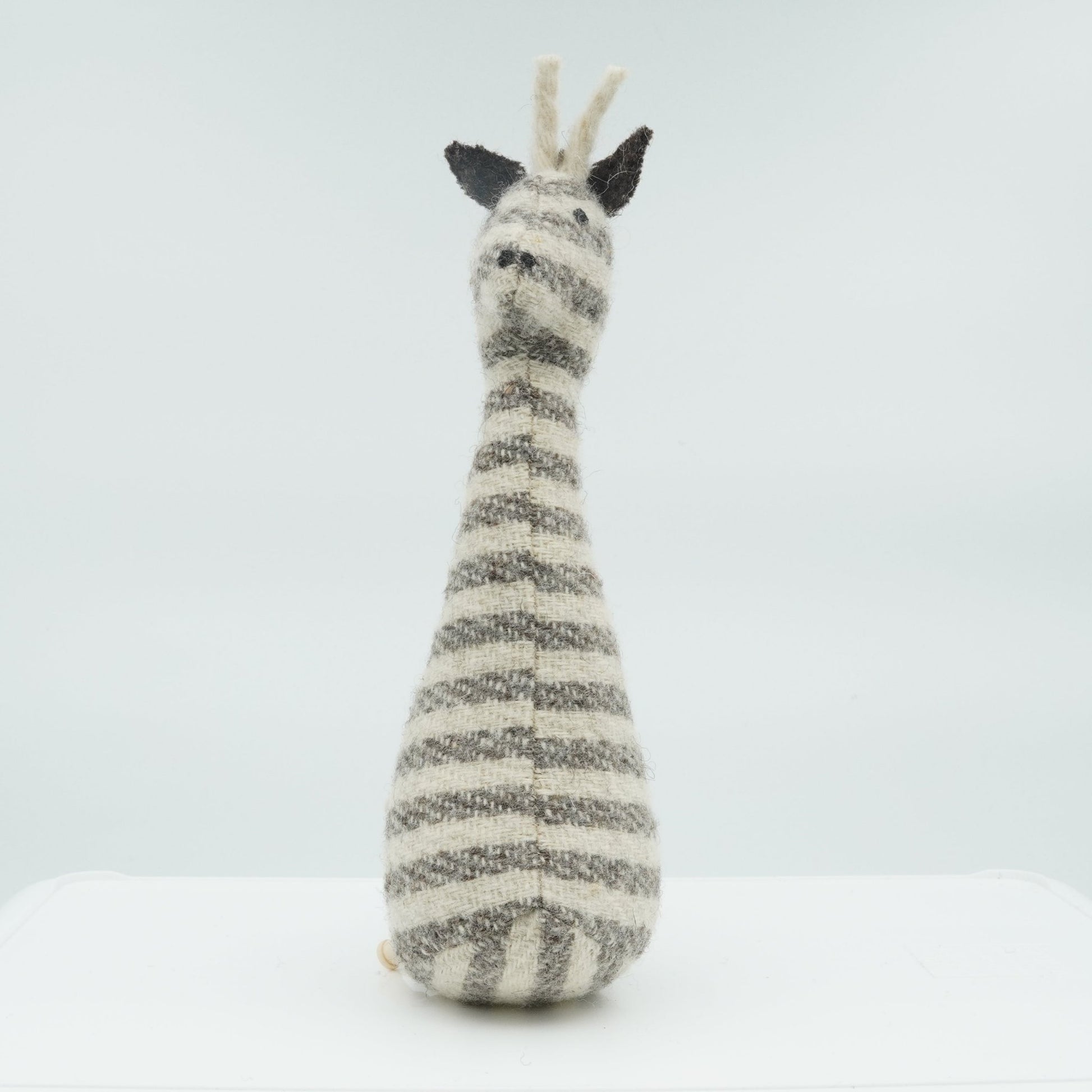 A gray and white wool rattle in the shape of a giraffe.