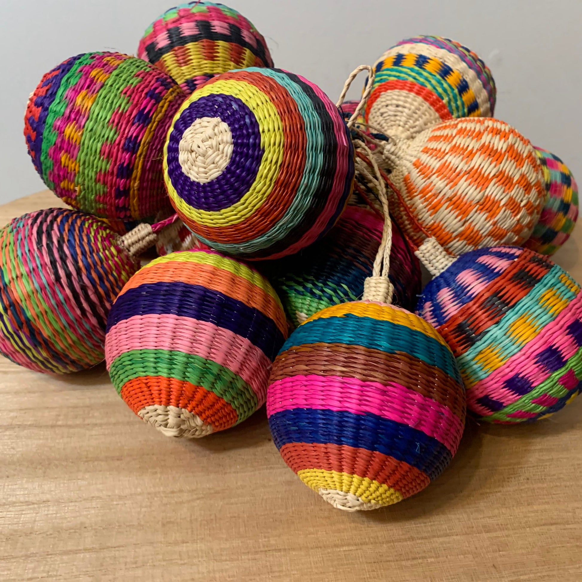 Group of colorful, ball-shaped woven ornaments made of iraca palm fiber.