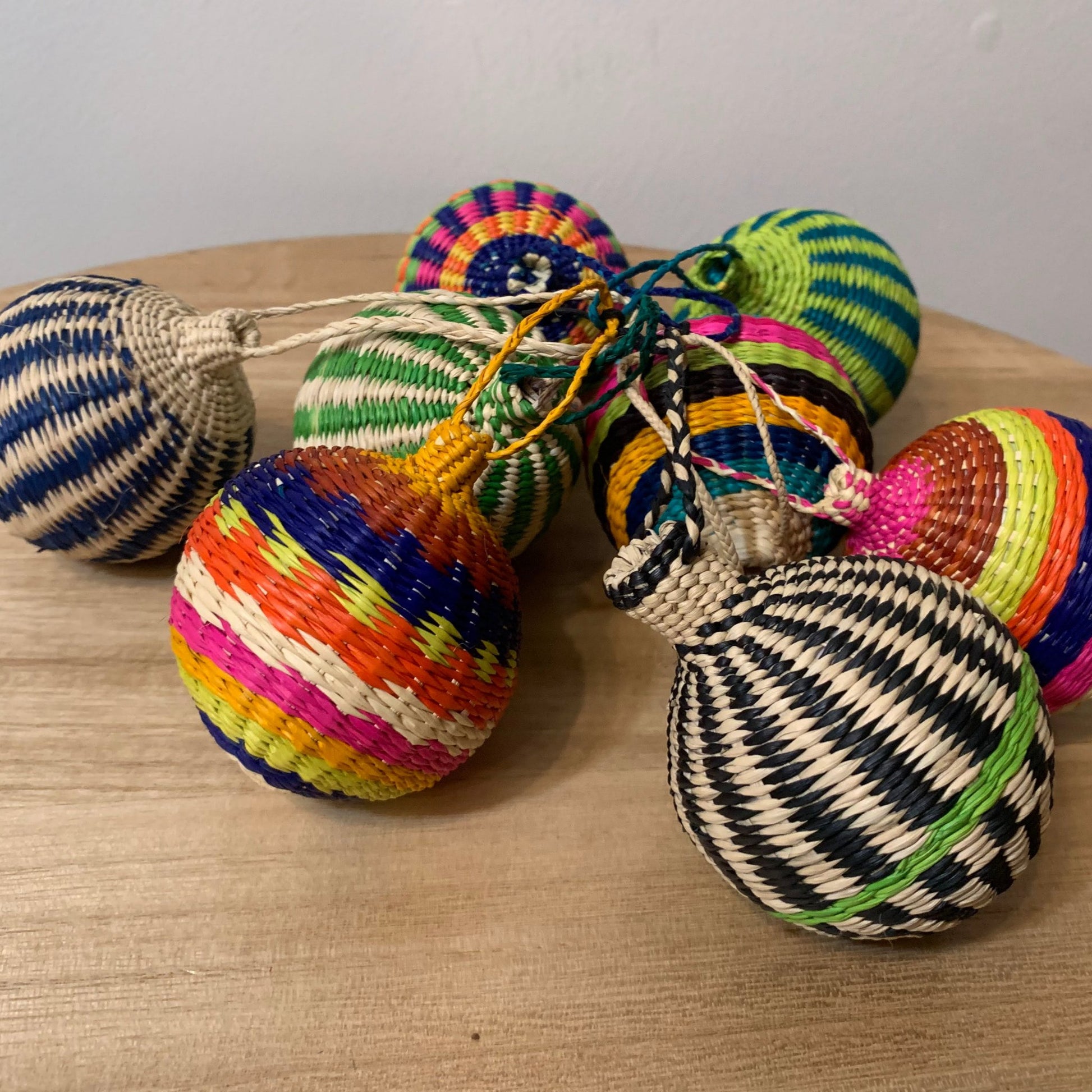 Group of colorful, ball-shaped woven ornaments made of iraca palm fiber.